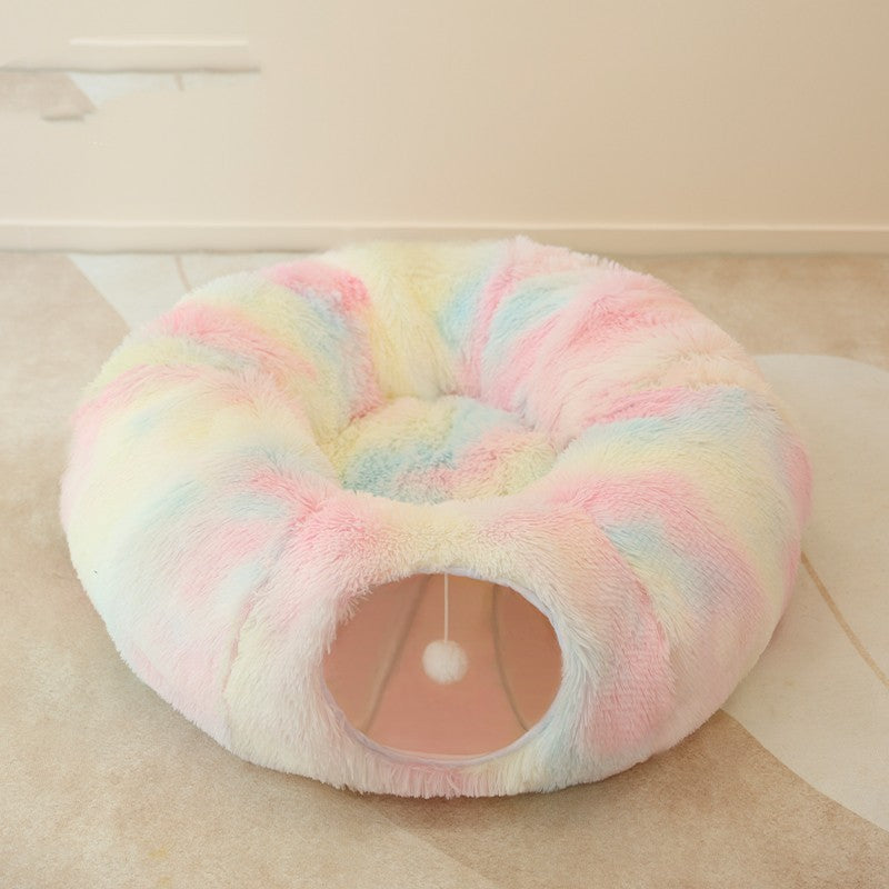 Pastel-colored donut-shaped pet bed on a light wooden floor.